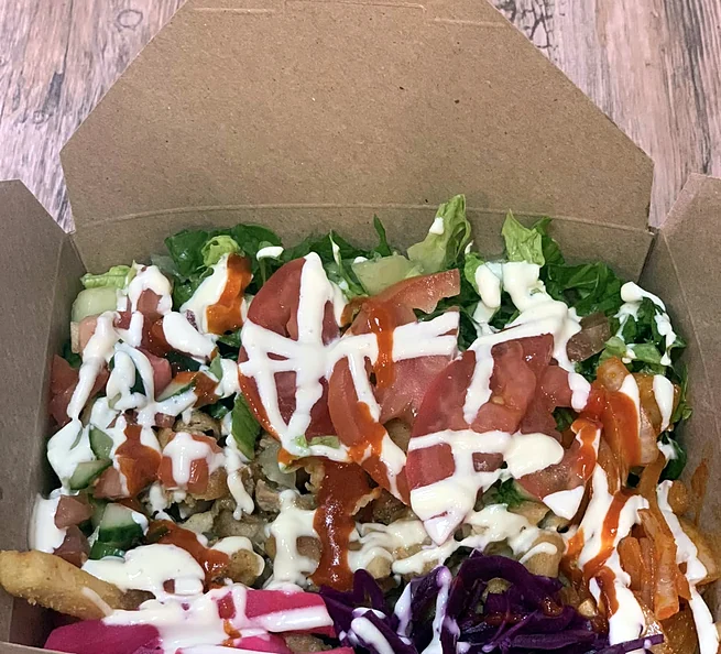 Donair box topped with salad, garlic sauce and hot sauce in a kraft box