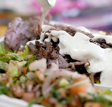 Garlic sauce poured over beef gyro